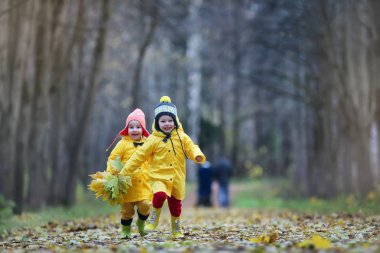 Çocuklar sonbahar parkında yürüyor.