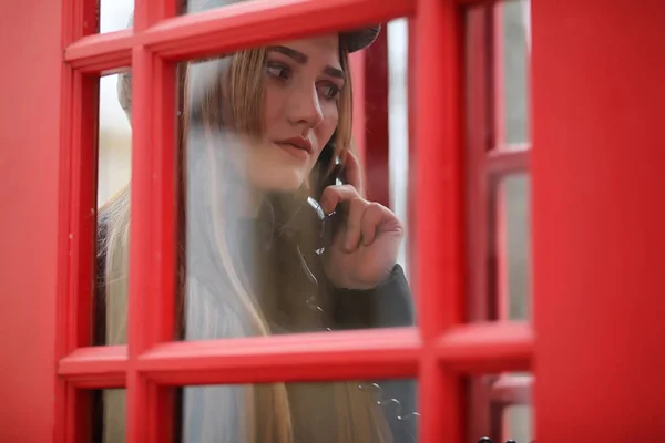 Όμορφη νεαρή κοπέλα σε ένα τηλεφωνικό θάλαμο. Το κορίτσι είναι μιλάμε για th — Φωτογραφία Αρχείου