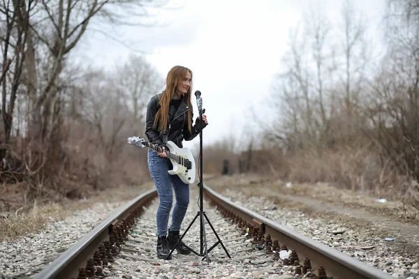 Uma menina músico de rock em uma jaqueta de couro com uma guitarra — Fotografia de Stock