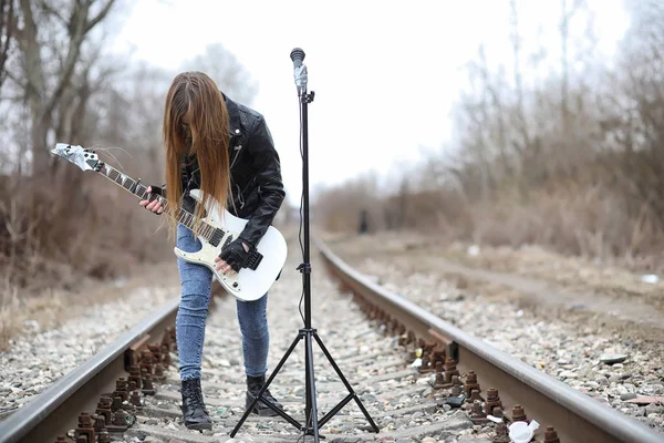 Uma menina músico de rock em uma jaqueta de couro com uma guitarra — Fotografia de Stock