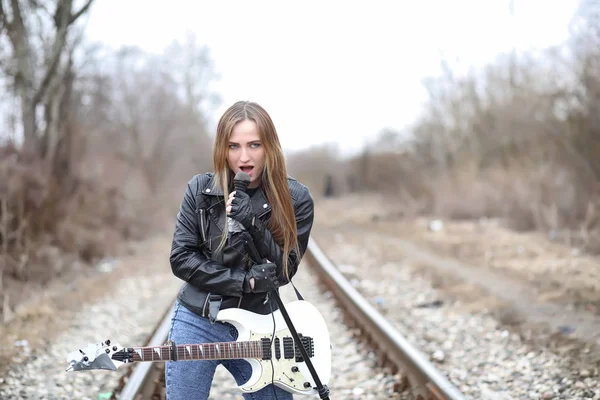 Una chica músico de rock en una chaqueta de cuero con una guitarra — Foto de Stock