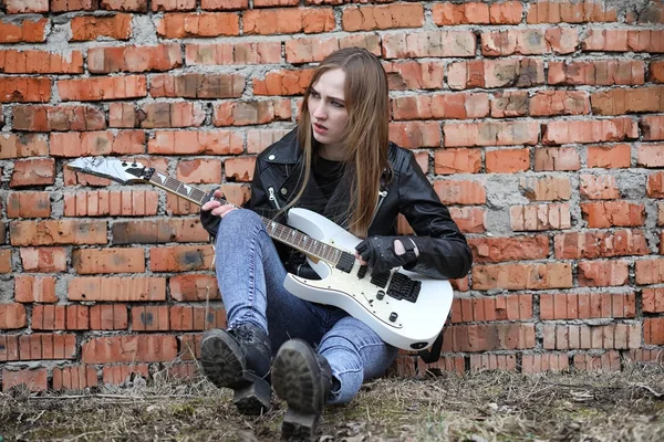 Uma menina músico de rock em uma jaqueta de couro com uma guitarra — Fotografia de Stock