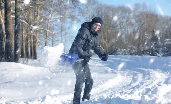 Man remove snow with shovel from the road in snowy winter — Stock Photo, Image