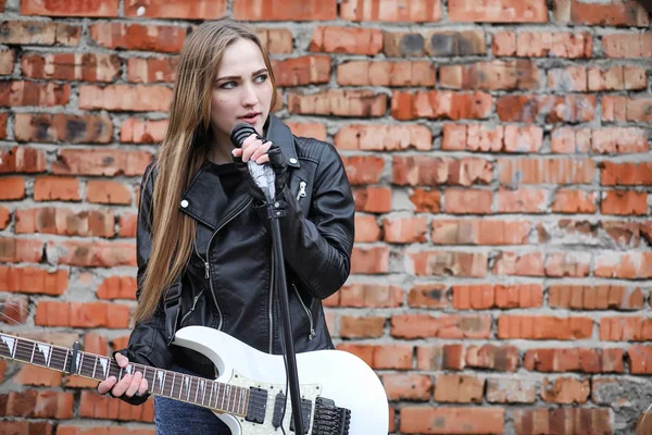 Uma menina músico de rock em uma jaqueta de couro com uma guitarra — Fotografia de Stock