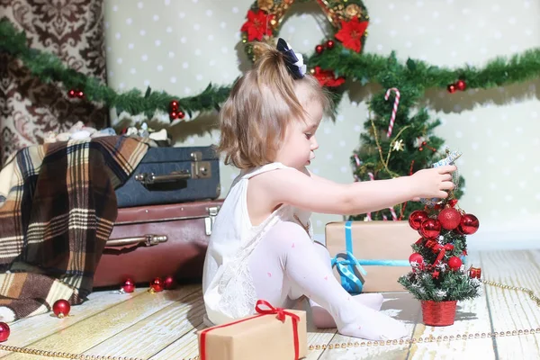 Niña sentada frente a un árbol de navidad — Foto de Stock