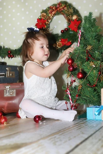 Niña sentada frente a un árbol de navidad — Foto de Stock