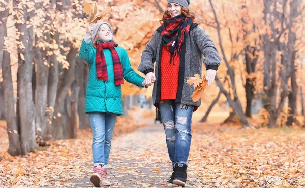 Chica en otoño parque de la ciudad en otoño de hojas. Joven hermosa madre wi — Foto de Stock