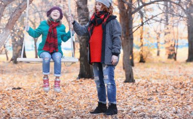 Kız sonbahar şehir parkında yaprak düşer. Genç güzel wi anne