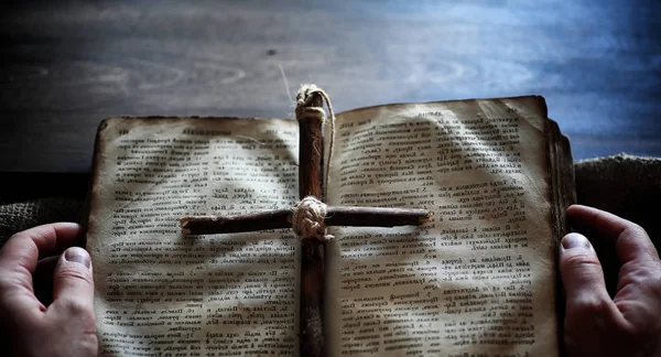 Antiguo libro religioso sobre una mesa de madera. Una cruz religiosa atada ingenio —  Fotos de Stock