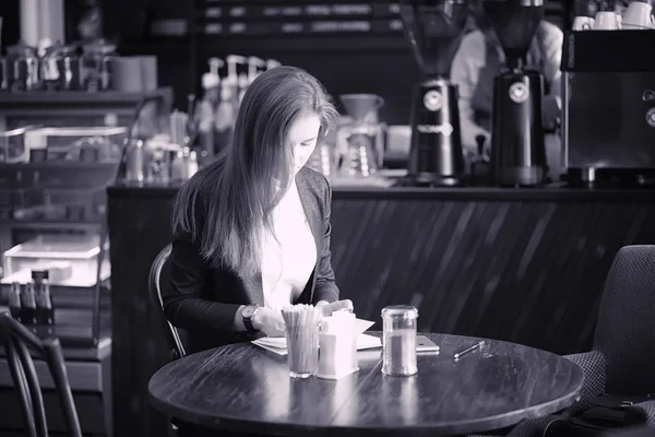 Uma rapariga num café está a beber café. Uma mulher está tomando café da manhã — Fotografia de Stock