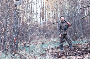 Kamuflaj ve bir sp üzerinde bir ormanda bir av tüfeği ile bir adam