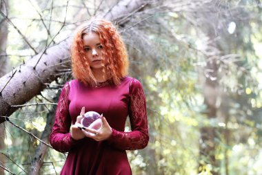 Kızıl saçlı cadı bir ritüel bir kristal top ile tutar