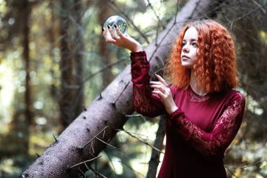 Kızıl saçlı cadı bir ritüel bir kristal top ile tutar