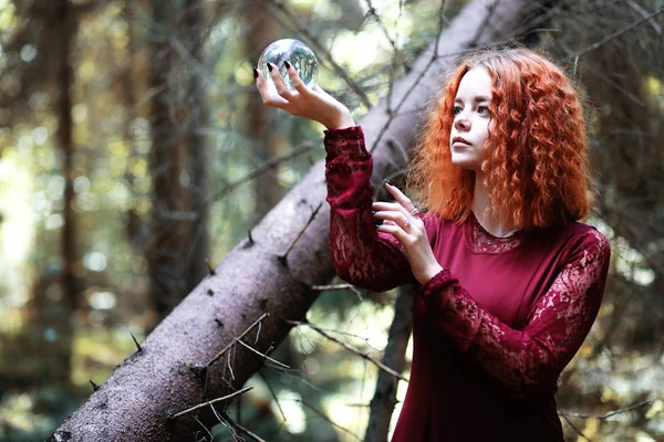 Kızıl saçlı cadı bir ritüel bir kristal top ile tutar