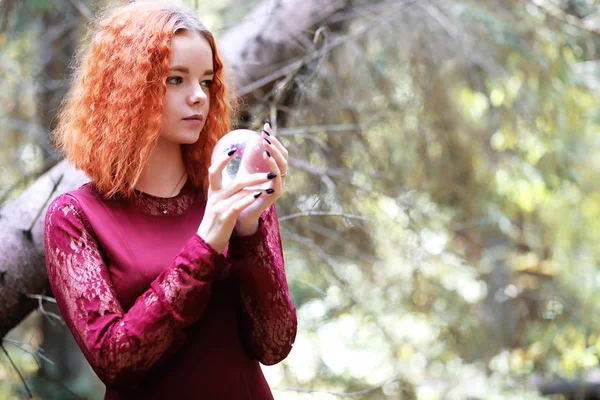 Kızıl saçlı cadı bir ritüel bir kristal top ile tutar