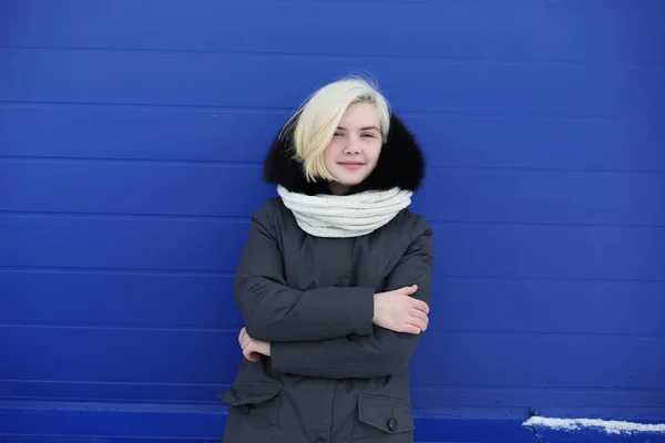 Junges schönes Mädchen auf einem Winterspaziergang an der blauen Wand — Stockfoto