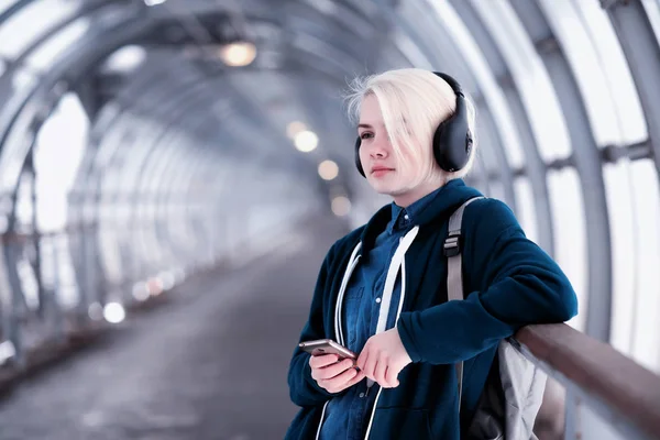 Young student listening to music in big headphones in the subway