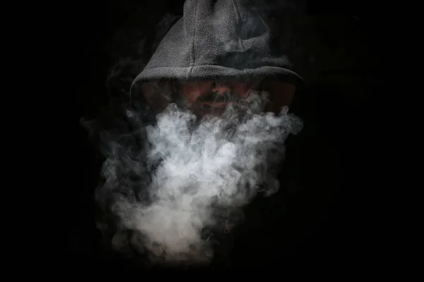 Człowiek w czarnym kapturem i dymu — Zdjęcie stockowe
