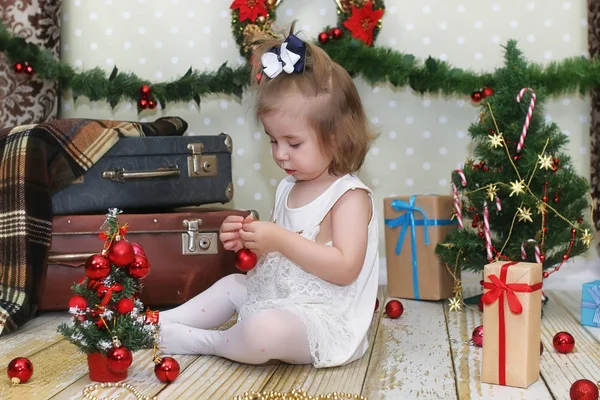 Little girl sitting in front of a Christmas tree — Stock Photo, Image