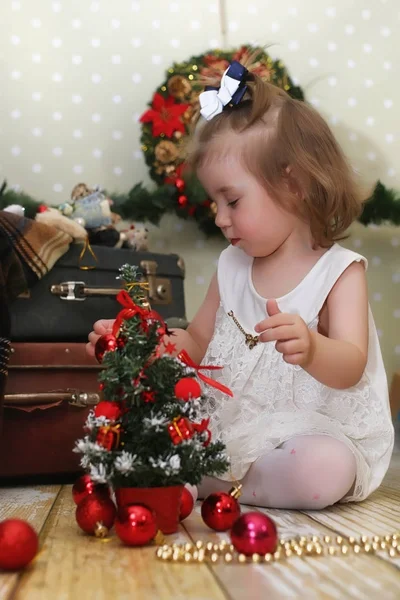 Niña sentada frente a un árbol de navidad — Foto de Stock