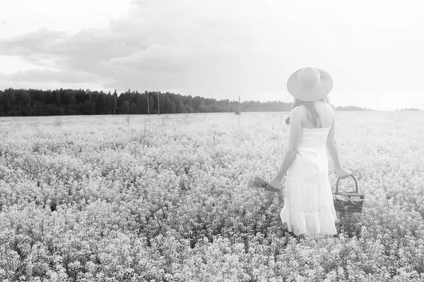 Monochrome portrait of young girl in a hat standing in a huge fi — Stock Photo, Image