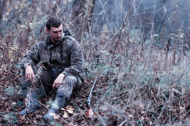 Kamuflaj ve bir sp üzerinde bir ormanda bir av tüfeği ile bir adam