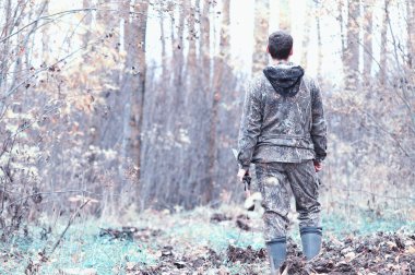 Kamuflaj ve bir sp üzerinde bir ormanda bir av tüfeği ile bir adam