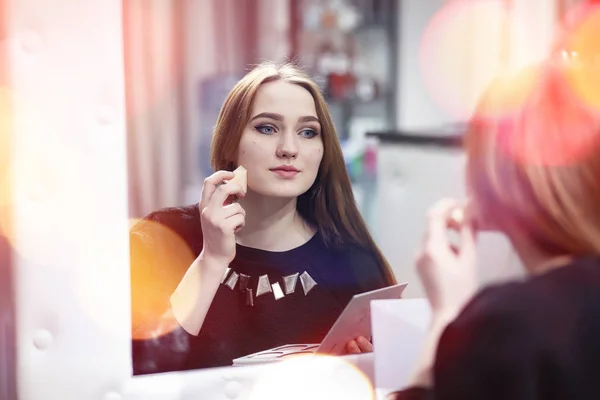 En ung pige gør make-up i en skønhedssalon. Pigen foran o - Stock-foto