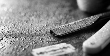 Tehlikeli bir ustura ve masanın üzerinde metal bir bıçak. Mens tıraş