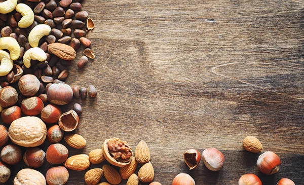 Olika nötter på ett träbord. Ceder, cashew, hasselnöt, walnu — Stockfoto