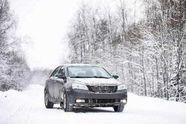 Bir karla kaplı yolda araba duruyor