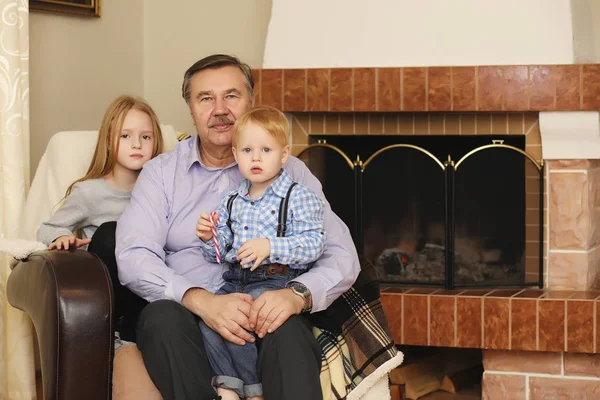 Familia calentada por la chimenea sentada en el sofá —  Fotos de Stock