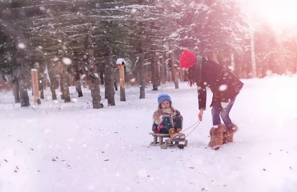 A winter fairy tale, a young mother and her daughter ride a sled