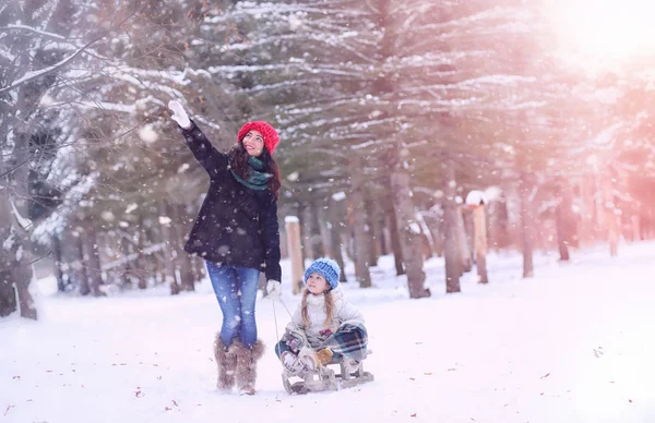 A winter fairy tale, a young mother and her daughter ride a sled