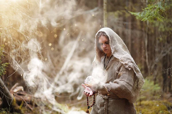 Un hombre en una sotana pasa un ritual en un bosque oscuro — Foto de Stock