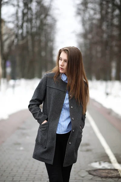 Молодая взрослая девушка в пальто на улице — стоковое фото