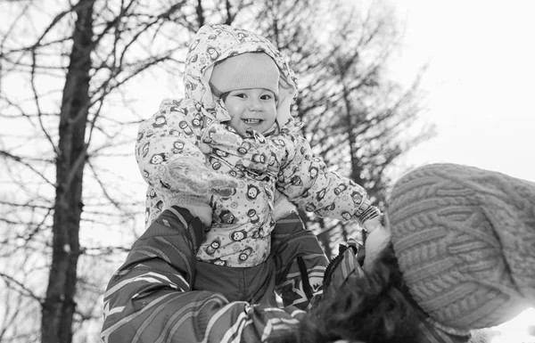 Foto en blanco y negro de los padres sosteniendo al niño en las manos en invierno p — Foto de Stock