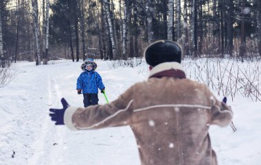 Çocuk kış parkında oynuyor ve ailesiyle eğleniyor.
