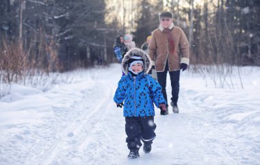 Çocuk kış parkında oynuyor ve ailesiyle eğleniyor.