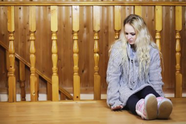 Genç bir kız kazakla merdivende oturuyor.