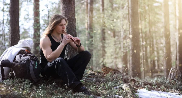 A musician with a tool in nature. A man is playing a flute in a — Stock Photo, Image