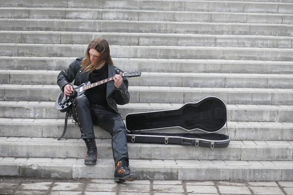 Guitarrista de rock nos degraus. Um músico com uma guitarra baixo em um — Fotografia de Stock