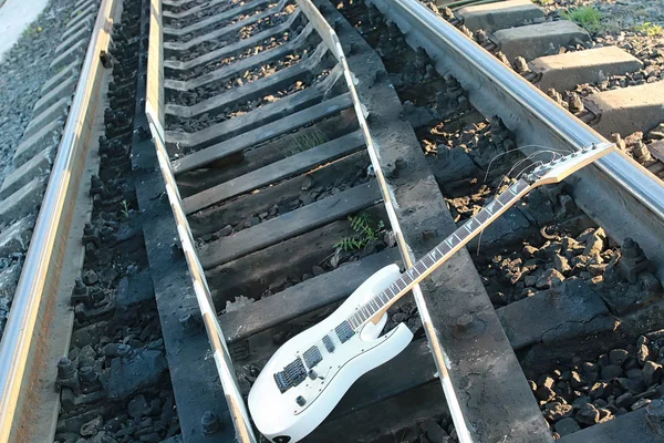 Guitarra elétrica branca nas trilhas ferroviárias e pedras — Fotografia de Stock