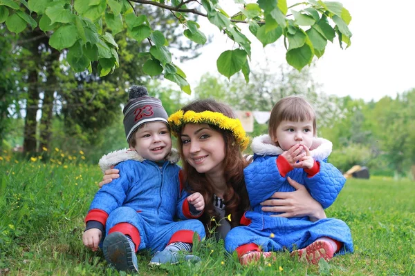 Мати з молодими близнюками, що сидять на зеленому лузі на ранньому спринді — стокове фото