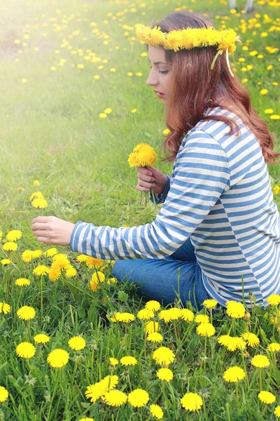 Gadis beristirahat pada hari yang cerah di padang rumput dari dandelion kuning — Stok Foto