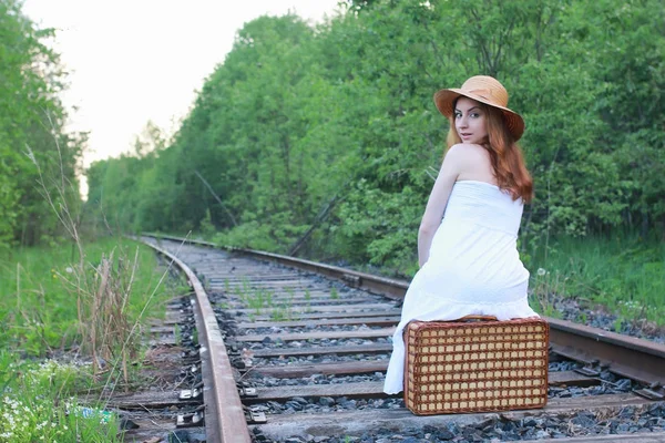 Dívka v bílém slunečním a proutěný kufr chůze na kolejích — Stock fotografie