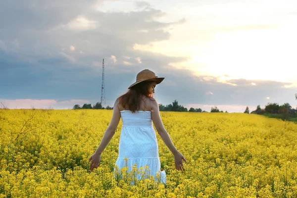 Ragazza in cappello di paglia in un campo di fiori gialli in fiore — Foto Stock