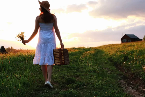 Ragazza in primavera sul campo. Una ragazza con una valigia cammina — Foto Stock