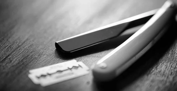 Una maquinilla de afeitar peligrosa y una hoja de metal sobre la mesa. afeitado para hombre —  Fotos de Stock