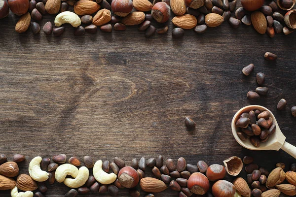 Olika nötter på ett träbord. Ceder, cashew, hasselnöt, walnu — Stockfoto